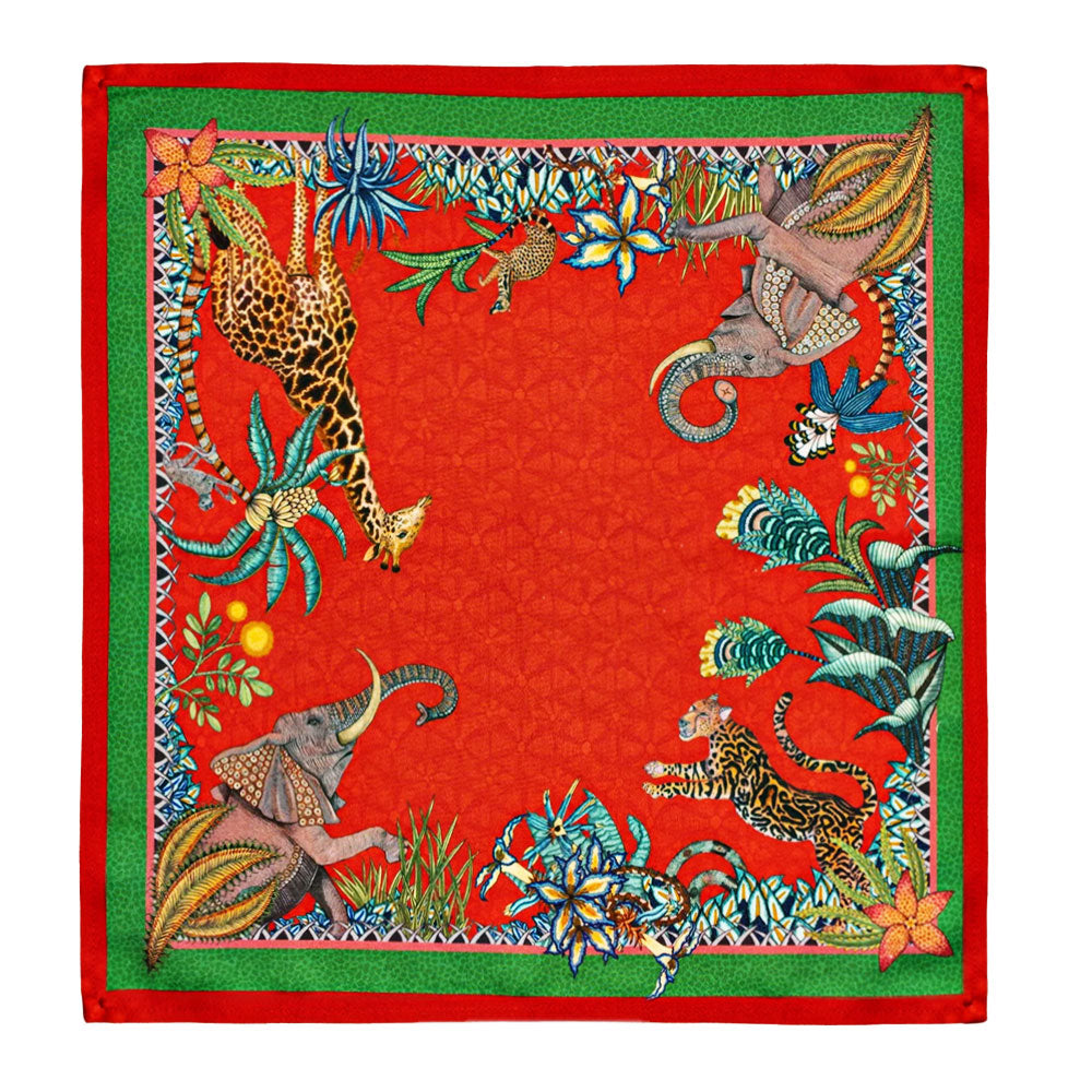 Sabie Forest Napkin featuring a vivid red background framed with green borders and illustrated African wildlife including a giraffe, elephants, and a tiger surrounded by lush tropical foliage.