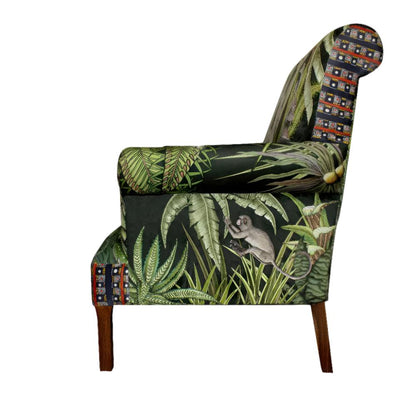 Side profile view of the Sabie Sofa displaying the outer arm upholstery with a monkey reaching through tropical green foliage.