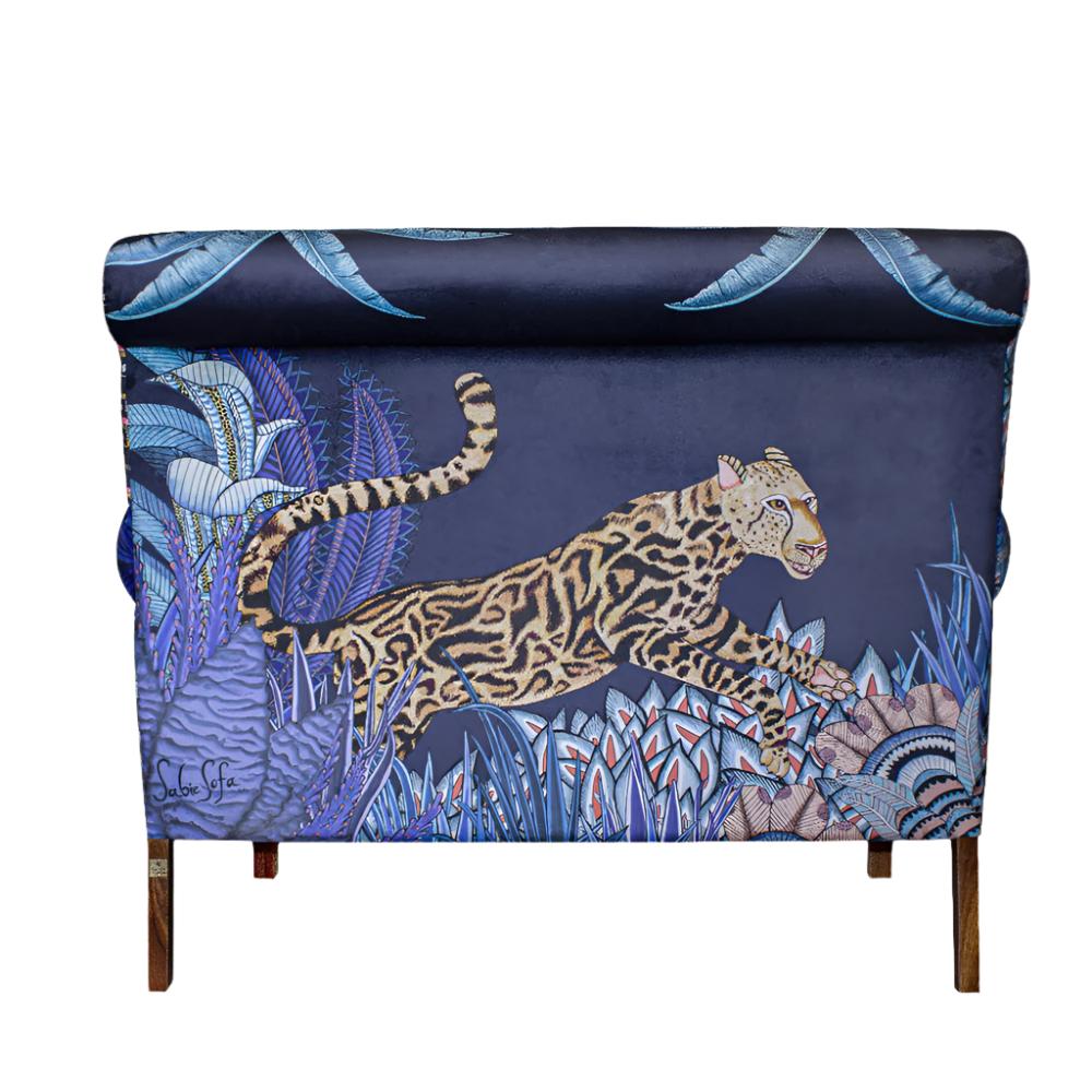 Back view of the Sabie Sofa upholstered in dark blue fabric featuring a large, detailed illustration of a leaping leopard amidst tropical flora.