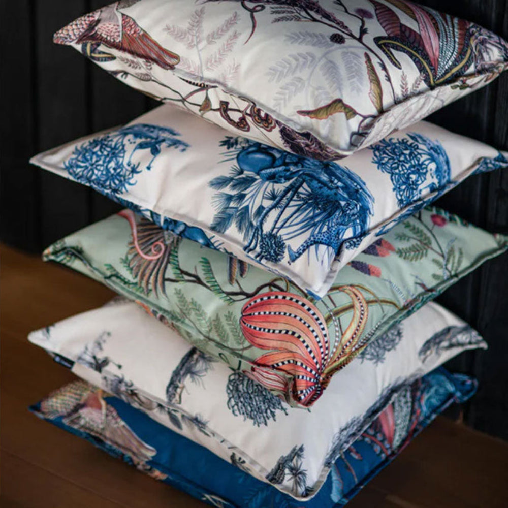 A stack of five Thanda Nest Pillows in various colorways, including cream, sage green, blue, and white botanical print designs.