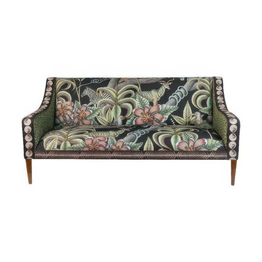 Front view of the Thanda Sofa featuring dark upholstery printed with vibrant safari wildlife, lush foliage, and pink flowers, set on dark wooden legs with patterned side panels.
