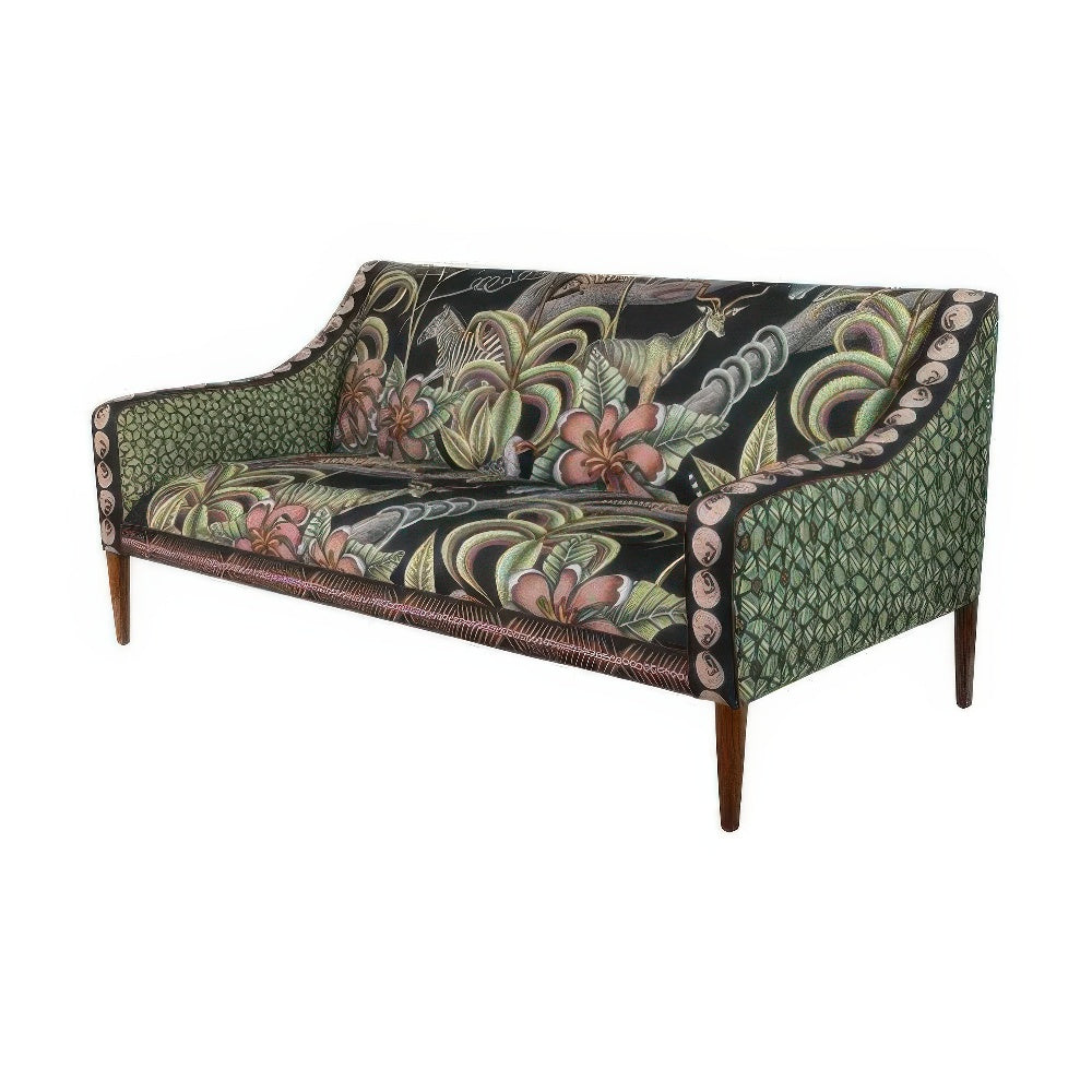 Three-quarter view of the Thanda Sofa showcasing its curved armrests, dark botanical and animal-print cushions, and geometric green pattern on the outer sides.