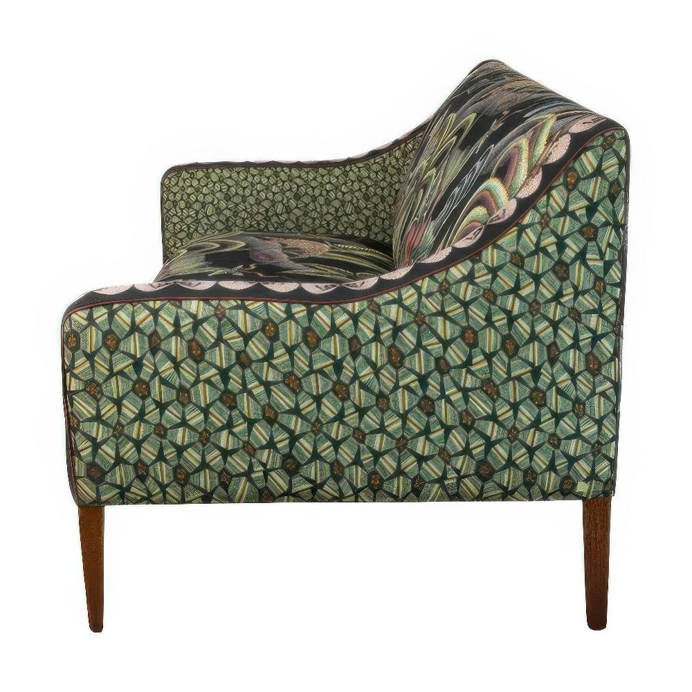 Side profile view of the Thanda Sofa displaying the green geometric patterned fabric covering the outer side panels and slender wooden legs.