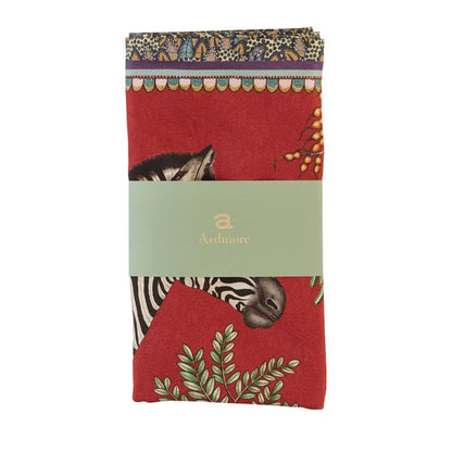 Folded Thanda Stripe napkins in royal red with zebra and botanical details wrapped in Ardmore packaging.