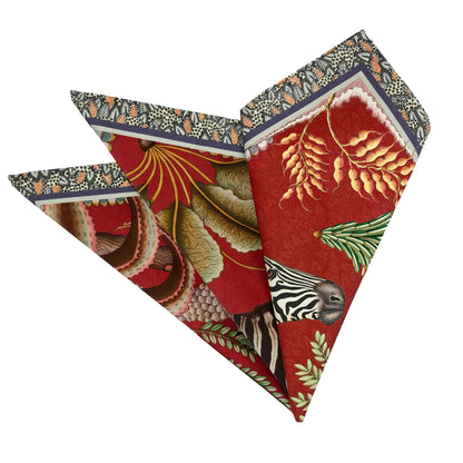 Folded royal red Thanda Stripe napkins showing zebra, pangolin, foliage, and patterned edging.