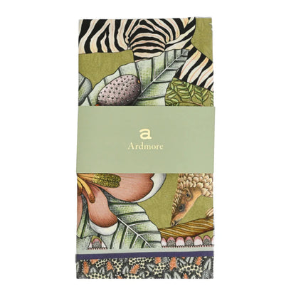 Folded Thanda Stripe Napkin by Ardmore wrapped with a light green branded paper band, showing sections of the zebra print, tropical leaves, flowers, and decorative border.