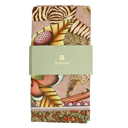 Folded Thanda Stripe Napkin by Ardmore wrapped with a light green branded paper band, showing sections of the zebra print, tropical leaves, flowers, and decorative border.