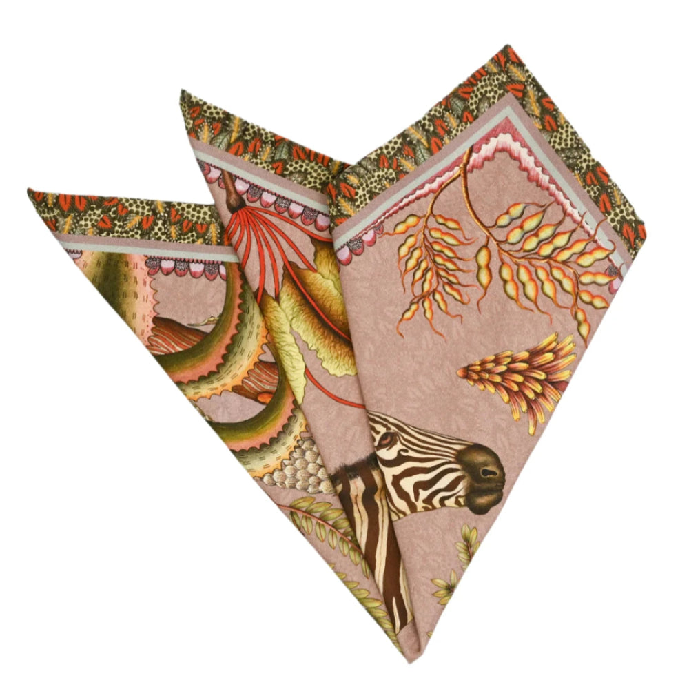 Thanda Stripe Napkin folded into a decorative fan shape, showing zebra artwork, tropical leaves, flowers, and warm pink, coral, green, and cream tones.