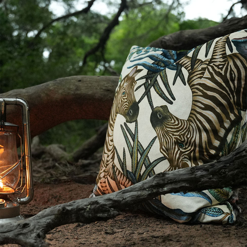 Thanda Stripe pillow styled outdoors with zebra print and foliage beside a lantern.