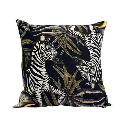 Thanda Stripe Pillow featuring two illustrated zebras surrounded by layered cream, olive, gold, and earthy botanical foliage on a deep navy background.