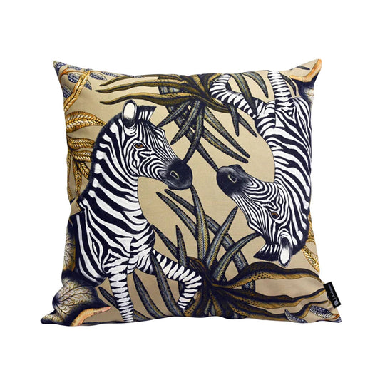 Thanda Stripe Pillow featuring two illustrated zebras surrounded by layered black, cream, gold, and olive botanical foliage on a warm beige background.