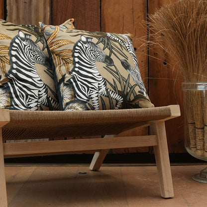 Thanda Stripe Pillows styled on a woven wooden bench against a warm wood-paneled wall, featuring zebra and botanical artwork in black, cream, gold, and beige tones.