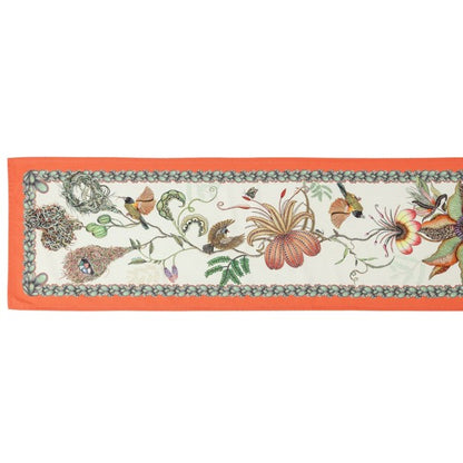 Full view of a long Ardmore table runner decorated with birds, nests, oversized flowers, foliage, and a bright coral-orange border.