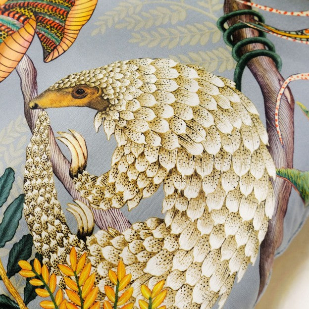 Close-up of the pillow’s detailed pangolin illustration, showing layered cream-colored scales, a curved body, and surrounding botanical accents.