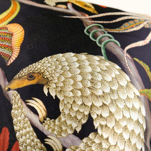 Close-up of the pillow’s detailed pangolin illustration, showing layered cream-colored scales, a curved body, and surrounding botanical accents.