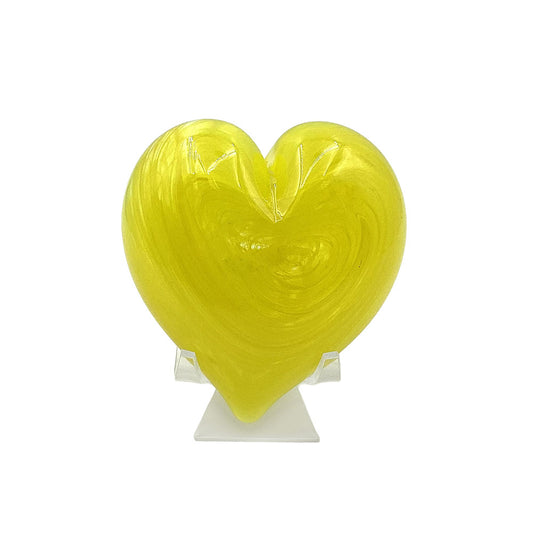 Translucent yellow heart-shaped decorative glass sculpture with swirling texture, displayed upright on a clear stand against a white background.